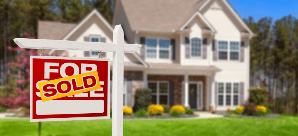 A “SOLD” sign in front of a suburban home, symbolizing a successful quick home sale that helps homeowners protect their finances and future.