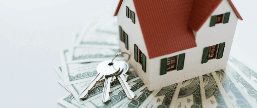 House keys resting on a pile of cash next to a model house, representing a fast, all-cash home closing and immediate payout for sellers.