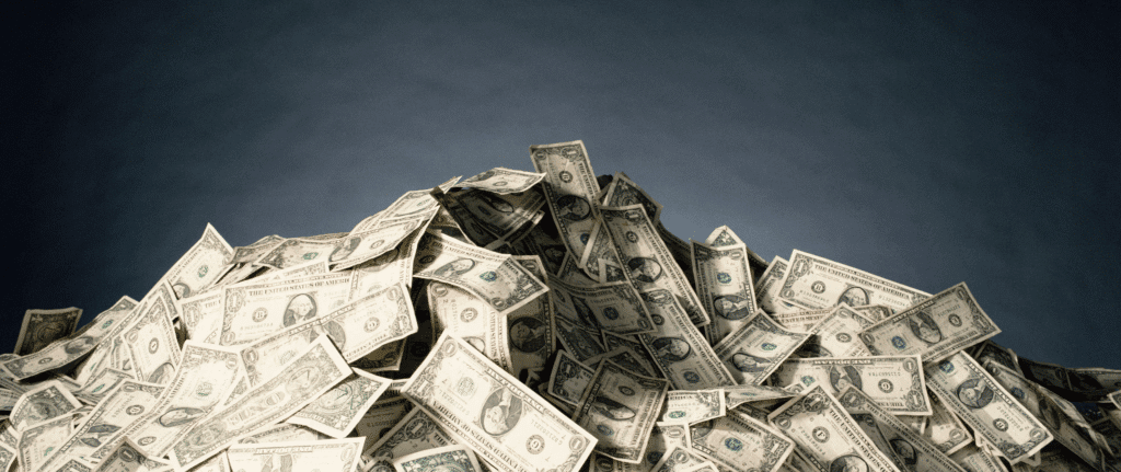 A large pile of U.S. dollar bills stacked against a dark background, symbolizing fast cash payments and immediate liquidity from a quick home sale.